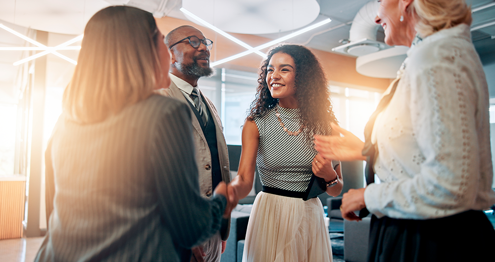 Imagem representando o sucesso profissional: jovens e adultos trocando cumprimentos em um ambiente corporativo moderno, demonstrando networking, confiança e crescimento na carreira. 